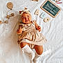 Kelya a rejoint le concours — aidez-le/la à gagner de superbes lots ! baby, infant, smiling, beige_dress, headband, white_socks, wooden_blocks, chalkboard, crayons, wafer, lying_down, white_sheet, child, cute, indoor, playful, education, back_to_school, happy, portrait