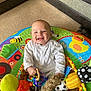 Carter joined the competition — help win amazing prizes! baby, smiling, toy, play_mat, indoor, carpet, couch, child, happy, colorful, infant, person, plush_toy, fabric, cute, sitting, face, head, hand, room