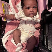 Nova is registered to the contest to win money with this photo: baby, infant, car_seat, blanket, onesie, towel, sock, child, cute, indoors, portrait, face, clothing, pink, white, soft_texture, seat, person, newborn, comfort