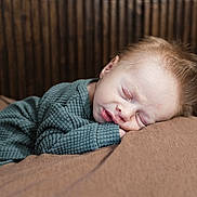 Everett is registered to the contest to win money with this photo: baby, sleeping, child, cozy, green_clothing, resting, soft_surface, wooden_background, peaceful, portrait, indoors, cute, infant, face, relaxing, warm_colors, closeup, young_child, comfort, serene