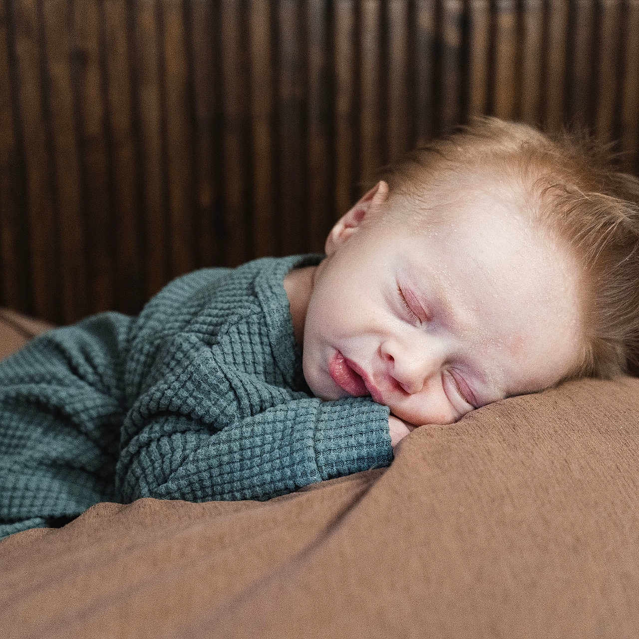 Everett is registered to the contest to win money with this photo: baby, sleeping, child, cozy, green_clothing, resting, soft_surface, wooden_background, peaceful, portrait, indoors, cute, infant, face, relaxing, warm_colors, closeup, young_child, comfort, serene