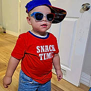 Liam is registered to the contest to win money with this photo: toddler, child, boy, red_shirt, snack_time, blue_cap, sunglasses, denim_shorts, socks, indoor, wooden_floor, door, white_door, standing, fashion, casual, cute, portrait, smiling, hat