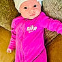 Jasmine is registered to the contest to win money with this photo: baby, infant, child, pink_clothing, nike, hat, white_hat, bow, couch, pillow, face, eyes, one_piece_outfit, indoor, portrait, cute, young_child, apparel, relaxing, lying_down