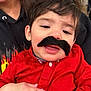 Milán joined the competition — help win amazing prizes! toddler, child, mustache, red_shirt, indoor, person, holding, cute, funny, face, expression, adult_hand, black_hair, smiling, casual_clothing, closeup, portrait, people, happy, playful