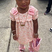 Deinovia joined the competition — help win amazing prizes! child, toddler, pink_clothing, heart_pattern, bracelets, necklace, purse, sandals, sidewalk, concrete, outdoor, person, curly_hair, vehicle, street, fashion, accessories, footwear, standing, casual