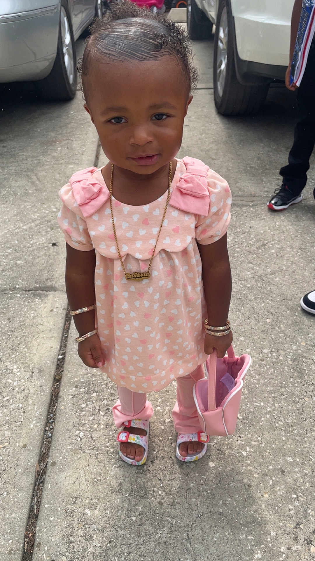 Deinovia joined the competition — help win amazing prizes! child, toddler, pink_clothing, heart_pattern, bracelets, necklace, purse, sandals, sidewalk, concrete, outdoor, person, curly_hair, vehicle, street, fashion, accessories, footwear, standing, casual