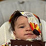 baby, child, face, cloth, colorful, turkey, pattern, brown_clothing, text, sitting, chair, portrait, infant, cute, indoors, comfort, young, expression, head, closeup