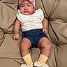 Elara Lucynn is registered to the contest to win money with this photo: baby, infant, child, couch, headband, bow, clothing, socks, yellow_socks, navy_shorts, cream_top, smiling, cute, indoor, plush, seated, comfortable, portrait, happy, cozy