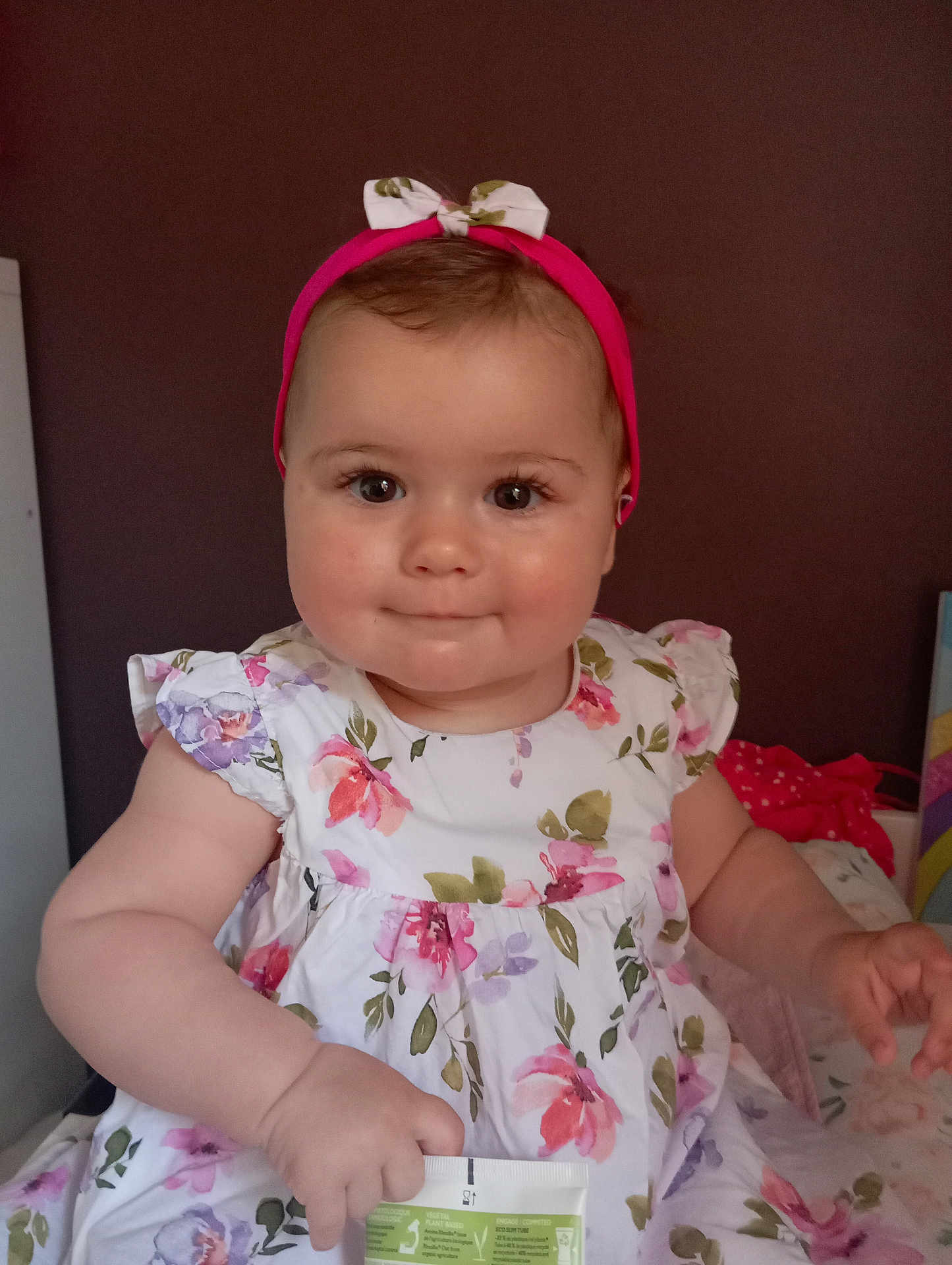 Aëlla participe au concours pour gagner de l'argent avec cette photo : baby, background, bow, child, cute, dress, face, floral_pattern, hand, headband, holding, indoor, infant, person, portrait, sitting, skin, smiling, soft_light, young_child