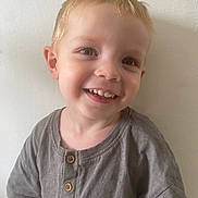 Nino a rejoint le concours — aidez-le/la à gagner de superbes lots ! child, toddler, smiling, happy, face, portrait, person, clothing, shirt, button, short_sleeve, blond_hair, light_skin, indoors, casual, cute, young_child, head_and_shoulders, background_wall, natural_light
