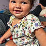Zyla is registered to the contest to win money with this photo: toddler, child, smile, curly_hair, floral_shirt, sitting, indoors, bed, water_bottle, happy, cute, portrait, face, skin, person, clothing, young_child, playful, expression, casual