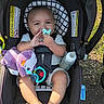 Karsen is registered to the contest to win money with this photo: baby, car_seat, pacifier, plush_toy, bottle, outdoor, grass, sunlight, happy, child, infant, seatbelt, smiling, toy, footwear, person, head, clothing, nature, baby_bottle