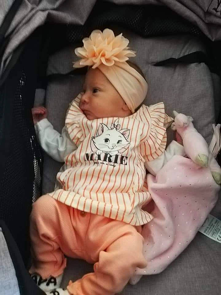 Mya a rejoint le concours — aidez-le/la à gagner de superbes lots ! baby, baby_products, baby_sleeping, baby_toddler_clothing, beanie, cheek, child, comfort, fashion_accessory, flower, head, headwear, lap, pattern, peach, person, pink, sitting, skin, sleeve