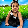 Mia is registered to the contest to win money with this photo: toddler, child, black_dress, headband, flower, grass, blue_surface, outdoor, cute, smiling, baby, nature, greenery, portrait, sitting, daylight, happy, innocent, playful, headwear