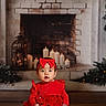 Sophia is registered to the contest to win money with this photo: baby, child, red_dress, headband, bow, fireplace, candles, holiday, festive, cozy, indoor, portrait, smiling, cute, floor, decor, greenery, warm, sitting, white_rug