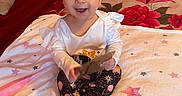 Sophia is registered to the contest to win money with this photo: baby, child, infant, bow_headband, white_top, patterned_pants, blanket, bedspread, elephant_illustration, stars, wooden_plaque, nine_months, indoor, smiling, sitting, cute, happy, portrait, milestone, person