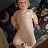 baby, infant, onesie, pink_clothing, polka_dots, face, lying_down, blanket, space_theme, moon, stars, cute, child, portrait, indoors, soft_lighting, young_child, expression, sleepwear, person
