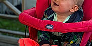 Fabio a rejoint le concours — aidez-le/la à gagner de superbes lots ! baby, child, stroller, red, orange_blanket, smiling, happy, outdoor, wooden_deck, car, clothing, hands, face, person, cute, infant, seated, hoodie, expression, daylight