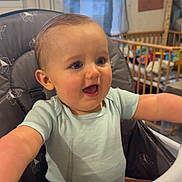 Fabio participe au concours pour gagner de l'argent avec cette photo : baby, high_chair, smiling, happy, child, indoor, blue_eyes, short_hair, onesie, feeding_chair, nursery, toy, window, daylight, furniture, face, person, infant, cute, expression
