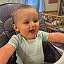 baby, high_chair, smiling, happy, child, indoor, blue_eyes, short_hair, onesie, feeding_chair, nursery, toy, window, daylight, furniture, face, person, infant, cute, expression