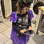 child, costume, halloween, face_paint, purple, black, spiderweb, crown, mirror, indoor, kitchen, tiles, jeans, shoes, long_sleeves, open_oven, household, curly_hair, standing, looking_down