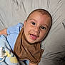 Juan is registered to the contest to win money with this photo: baby, smiling, face, bib, blanket, pacifier, lying_down, happy, infant, clothing, bed, cute, child, portrait, skin, head, eyes, mouth, early_childhood, toddler