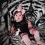 baby, child, infant, pink_bow, black_outfit, pink_socks, knitted_socks, fuzzy_blanket, tiger_print, animal_pattern, face, portrait, cute, indoor, seated, looking_at_camera, soft_texture, child_fashion, adorable, young_child