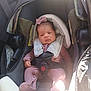 infant, baby, car_seat, five_point_harness, bow, pink_outfit, onesie, newborn, car_interior, sunlight, shadow, seat, head_support, safety_label, hand, foot, face, eyes, portrait, cute