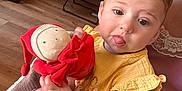 Lilyrose a rejoint le concours — aidez-le/la à gagner de superbes lots ! adult_hand, baby, bag, casual_wear, chair, child, cozy_room, curly_hair, face, glasses, hand, indoor, person, plush_toy, seated, table, tongue_out, toy, wooden_floor, yellow_clothing