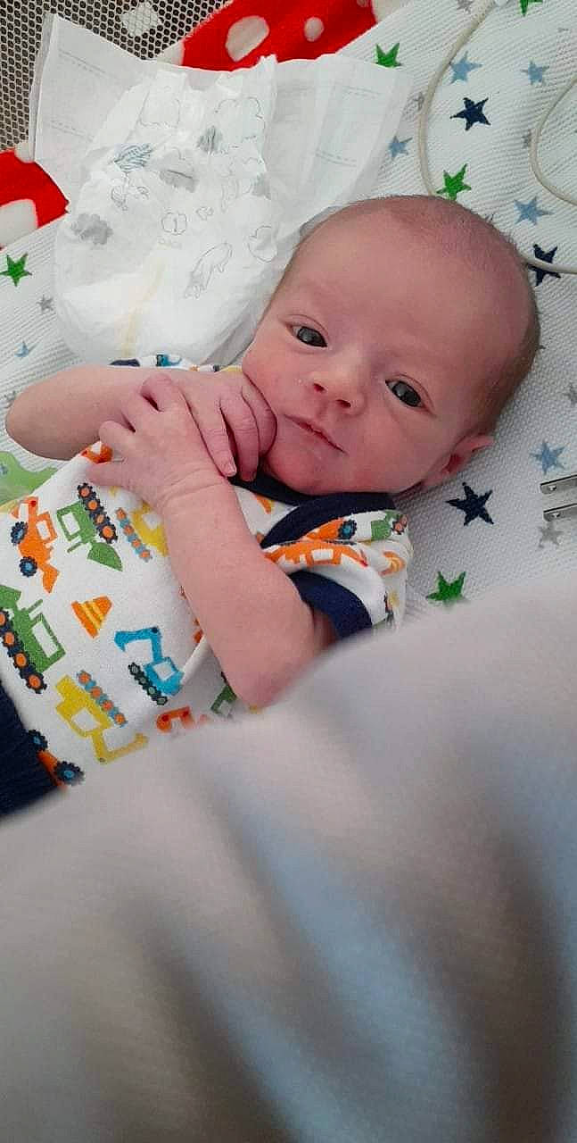 Raigen is registered to the contest to win money with this photo: baby, baby_toddler_clothing, cheek, child, comfort, eye, face, happy, head, linens, nail, pattern, person, portrait_photography, room, sitting, skin, sleeve, textile, toddler