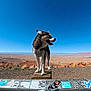 dog, outdoor, desert, sky, clear_sky, wood, stickers, railing, landscape, animal, pet, nature, sunny, standing, brown, white, happy, tongue_out, wide_open_space, scenic_view