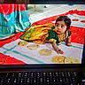 baby, child, infant, traditional_clothing, green_outfit, jewelry, bindi, wide_eyes, sitting, lying_down, indoor, colorful, blanket, textile, flatbread, food, celebration, portrait, keyboard, screen