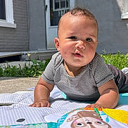 Aryah is registered to the contest to win money with this photo: baby, child, play_mat, outdoor, grass, striped_shirt, curious_expression, drool, concrete, house, door, window, pants, shoes, sunlight, greenery, infant, crawling, cute, portrait