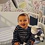 Enéa a rejoint le concours — aidez-le/la à gagner de superbes lots ! baby, child, crib, toy, stuffed_animal, mobile, pajamas, smiling, happy, indoor, infant, rattle, striped_clothing, face, sitting, nursery, decor, wooden_toy, playful, cute