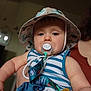 Malo participe au concours pour gagner de l'argent avec cette photo : accessory, adult, baby, blue, child, closeup, cute, expressionless, face, hand, hat, holding, indoor, infant, pacifier, person, skin, soft_lighting, striped_clothing, wearing