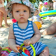 Malo a rejoint le concours — aidez-le/la à gagner de superbes lots ! baby, beach, child, colorful, greenery, hat, inflatable, mat, outdoor, people, play, sand, serious_expression, striped_clothing, summer, sunhat, sunny, toddler, toy, trees