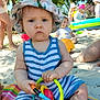baby, beach, child, colorful, greenery, hat, inflatable, mat, outdoor, people, play, sand, serious_expression, striped_clothing, summer, sunhat, sunny, toddler, toy, trees