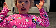Millie joined the competition — help win amazing prizes! child, surprised, pink_shirt, unicorn, indoor, living_room, television, carpet, furniture, expression, person, young, casual_clothing, home, cute, funny_face, hands_up, hair_up, carpeted_floor, wall