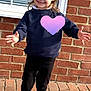 Millie is registered to the contest to win money with this photo: child, girl, smiling, pigtails, bows, navy_sweater, black_pants, black_shoes, white_socks, brick_wall, window, outdoor, sunlight, happy, posing, standing, pavement, casual_clothing, cute, portrait