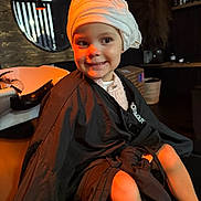 Millie joined the competition — help win amazing prizes! child, smile, towel, cape, salon, hair_wash_station, mirror, indoor, lighting, orange_light, happy, sitting, young, cute, face, clothing, person, hair_care, reflection, cozy