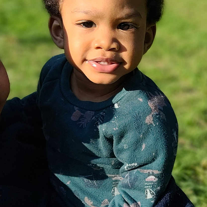 Raphaël participe au concours pour gagner de l'argent avec cette photo : blanket, casual_clothing, child, curly_hair, cute, daylight, face, greenery, happy, head, nature, outdoor, person, portrait, skin, smiling, sunlight, sweater, toddler, young
