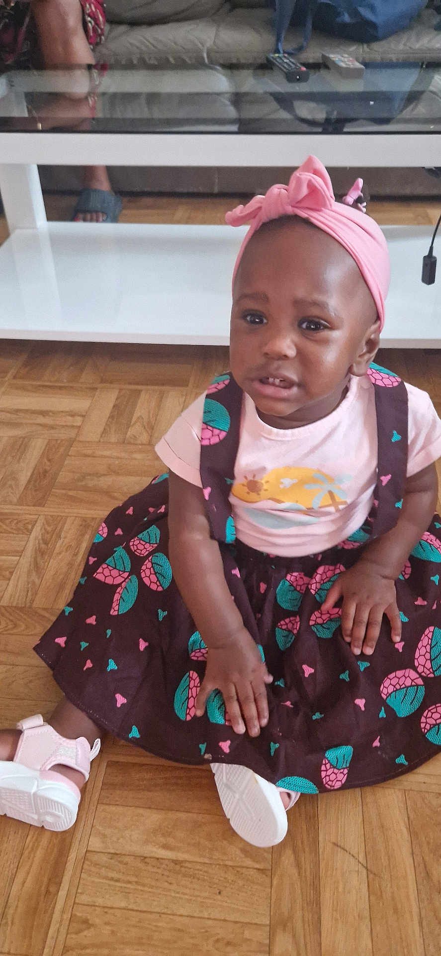 Marlène participe au concours pour gagner de l'argent avec cette photo : child, toddler, girl, dress, headwrap, pink, patterned_clothing, floor, wood_floor, sitting, indoor, furniture, table, couch, footwear, shoe, person, cute, portrait, living_room