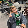 Ada-grace joined the competition — help win amazing prizes! child, cheerleader, green_uniform, peace_sign, posing, indoor, chair, people, event, casual_clothing, blonde_hair, smile, gesture, table, background, black_chair, hoodie, youth, person, portrait