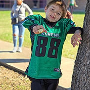 Benjamin joined the competition — help win amazing prizes! child, boy, football_jersey, green_jersey, number_88, championship_ring, tree, outdoor, daylight, smiling, leaning, people, background, sidewalk, grass, casual_clothing, happy, sports, young, posing