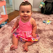 Alaiah joined the competition — help win amazing prizes! baby, child, smiling, pink_dress, bow, hair_accessory, sitting, rug, fluffy_rug, indoors, floor, happy, cute, person, portrait, skin, barefoot, clothing, room, toy