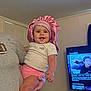 Alaiah joined the competition — help win amazing prizes! baby, child, toddler, pink_bonnet, pink_shorts, gray_shirt, football_graphic, smiling, happy, indoor, television, documentary, person_holding, home, living_room, screen, electronics, cute, portrait, family