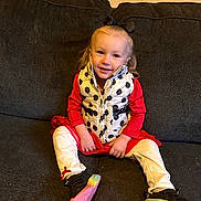 Kira joined the competition — help win amazing prizes! child, smiling, sitting, indoor, couch, vest, polka_dot, red_clothing, white_pants, black_shoes, bow, hair_accessory, happy, person, footwear, casual, young, portrait, cute, cozy