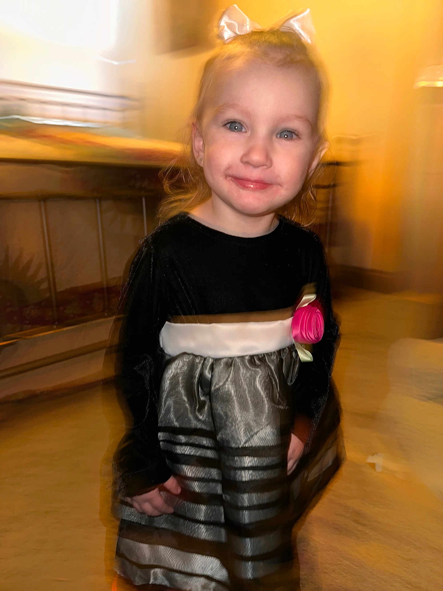 Kira is registered to the contest to win money with this photo: child, girl, smiling, dress, bow, indoor, portrait, face, happy, blonde_hair, pink_rose, long_sleeves, motion_blur, carpet, furniture, home, person, cute, fashion, event