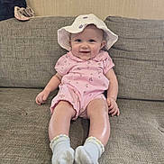 Emmie joined the competition — help win amazing prizes! baby, infant, smiling, pink_onesie, white_hat, socks, sofa, couch, indoor, child, cute, happy, portrait, seated, face, person, clothing, homedecor, furniture, baby_girl