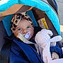 baby, infant, stroller, car_seat, pacifier, headwrap, blanket, plush_toy, blue_eyes, jacket, canopy, sunlight, hand, seat_belt, warning_label, outdoor, portrait, cozy, hood, fabric